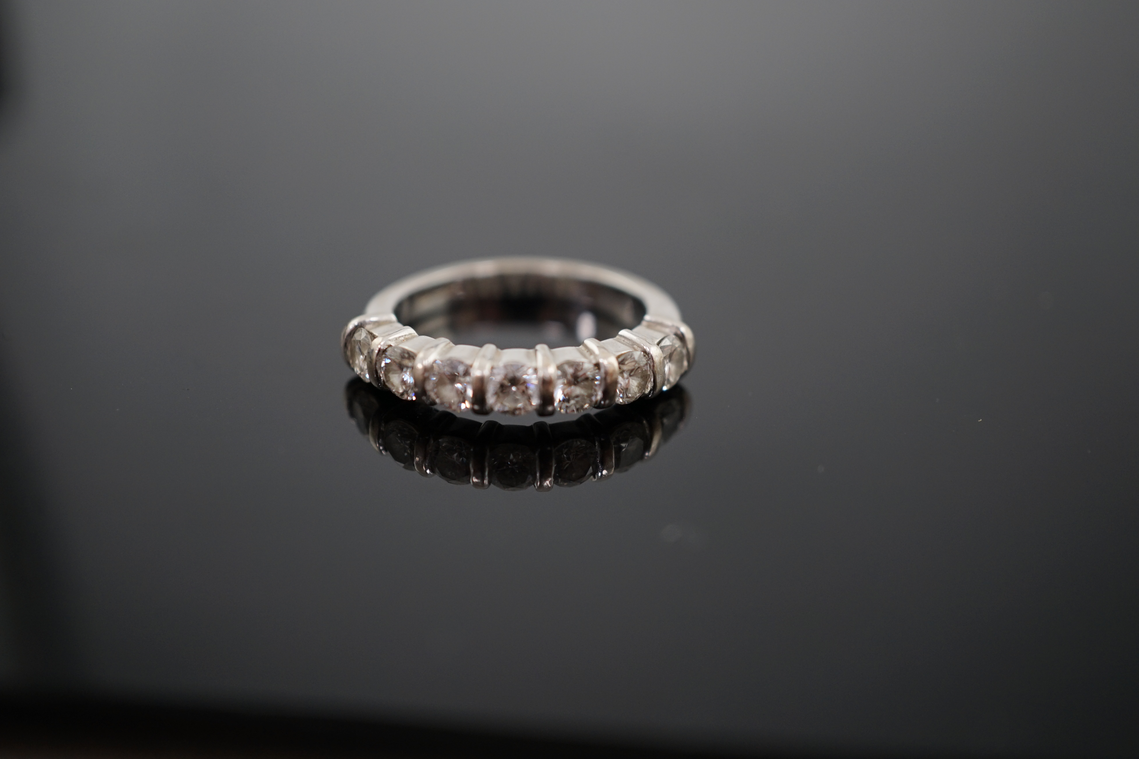 A modern 18ct white gold and seven stone round brilliant cut diamond set half hoop ring